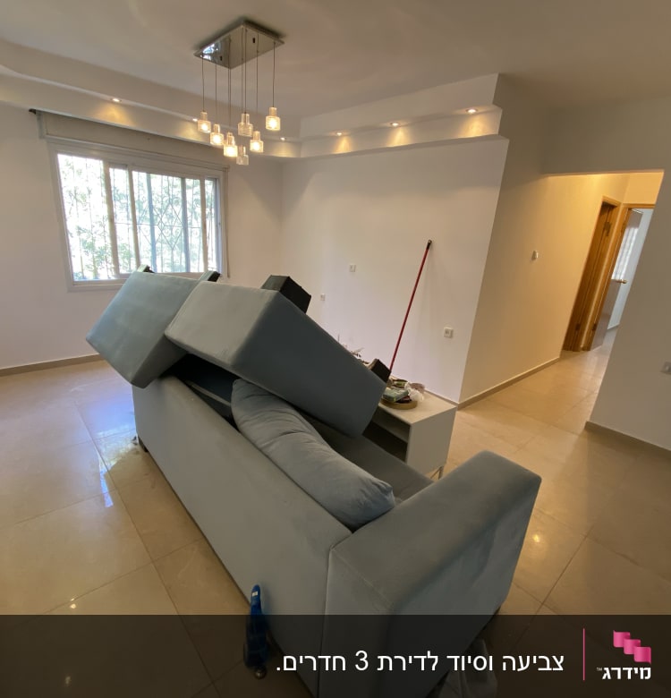 ספה הפוכה, מטאטא, קיר צבוע, חלון עם סורגים